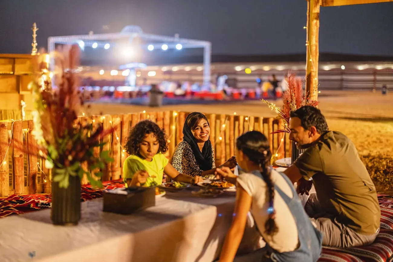 Guests gathered around a table at a desert camp